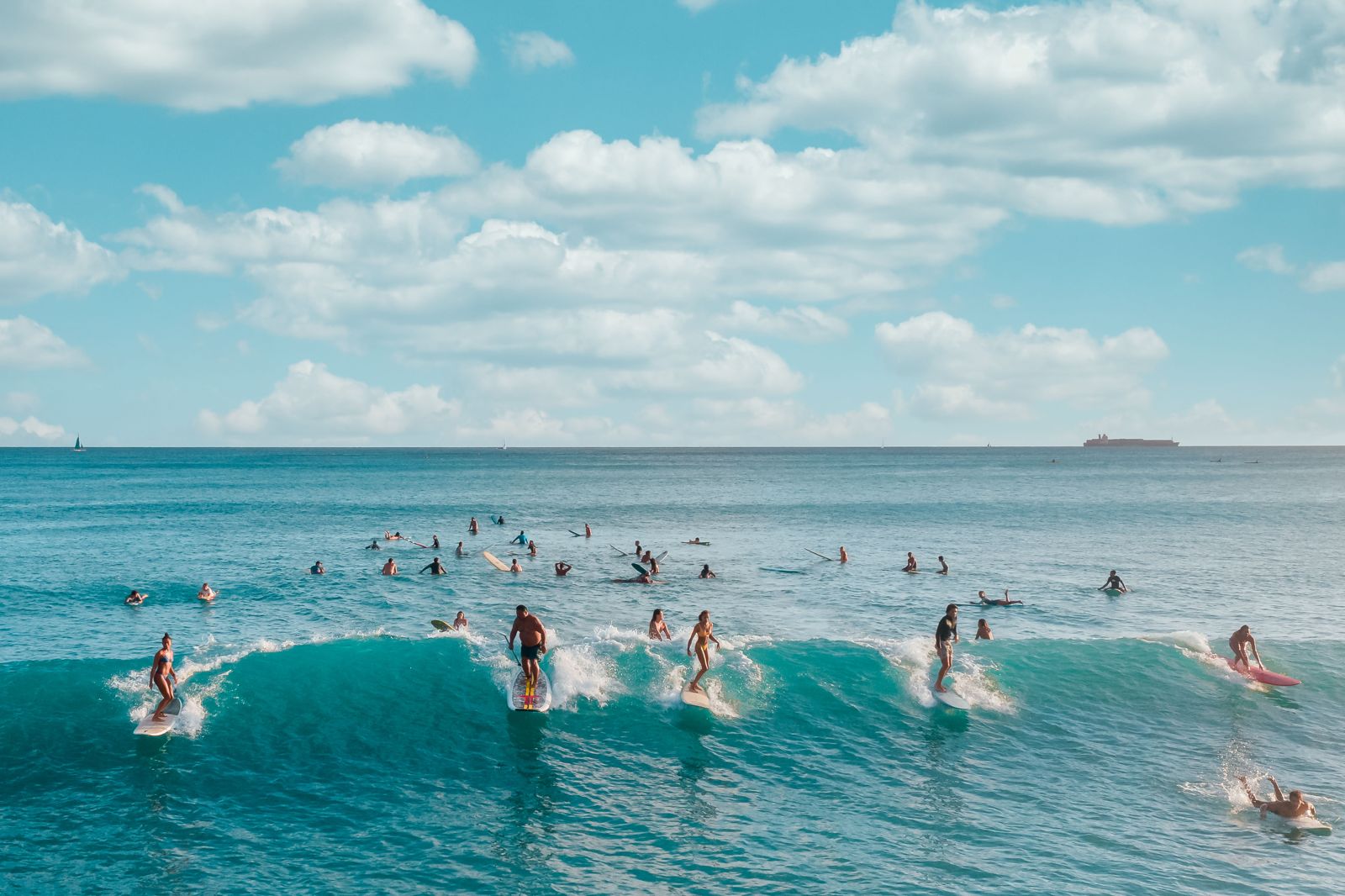 Varios surfistas agarrando la misma ola