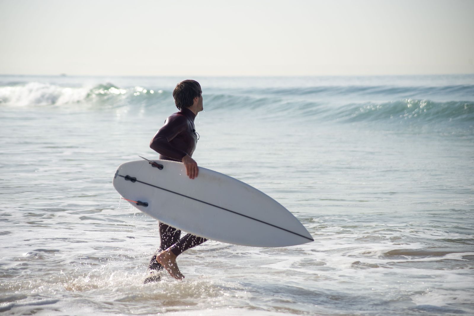 Surfista corriendo hacia el agua con su tabla