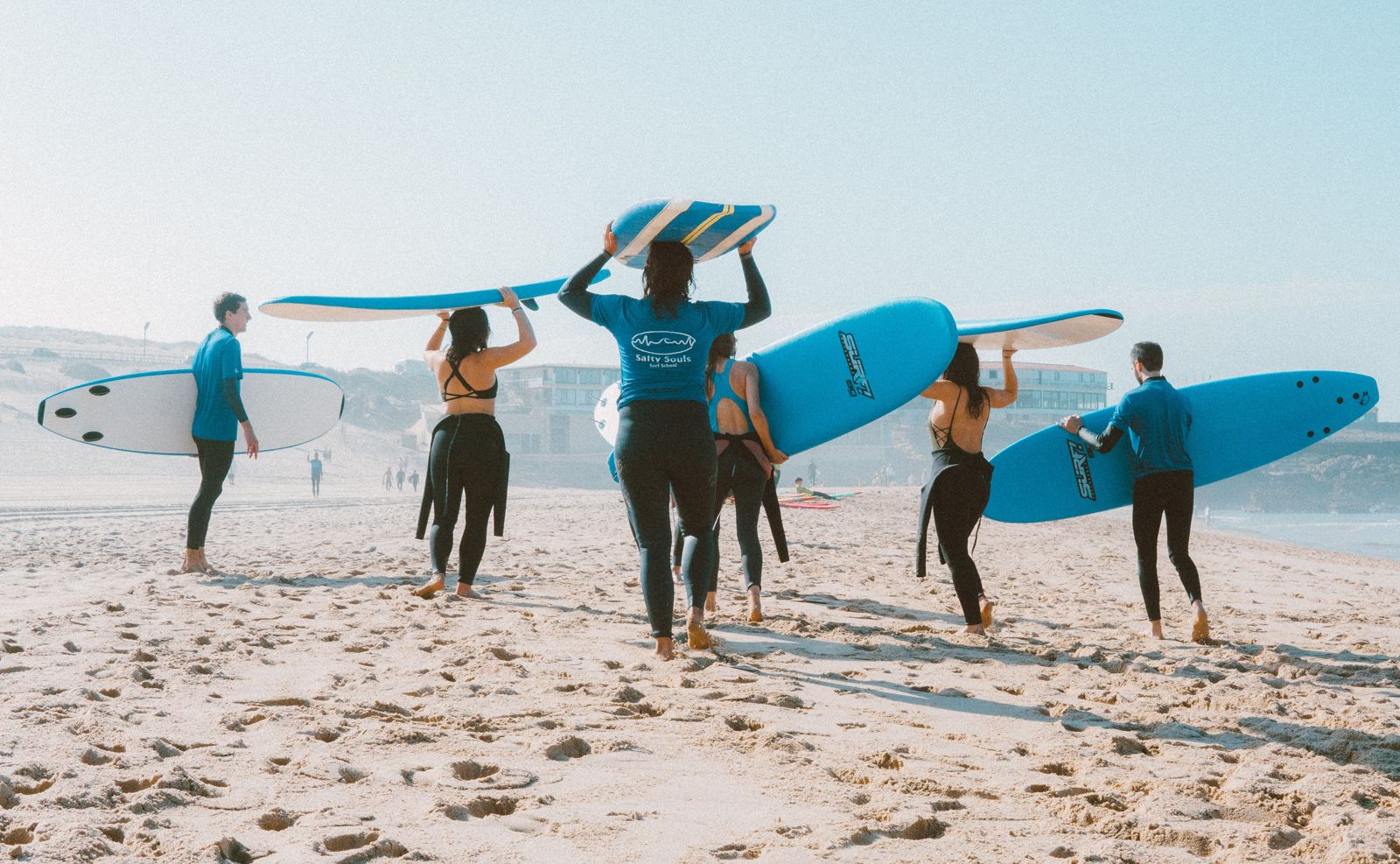 Grupo de alumnos caminando hacia el mar con sus tablas